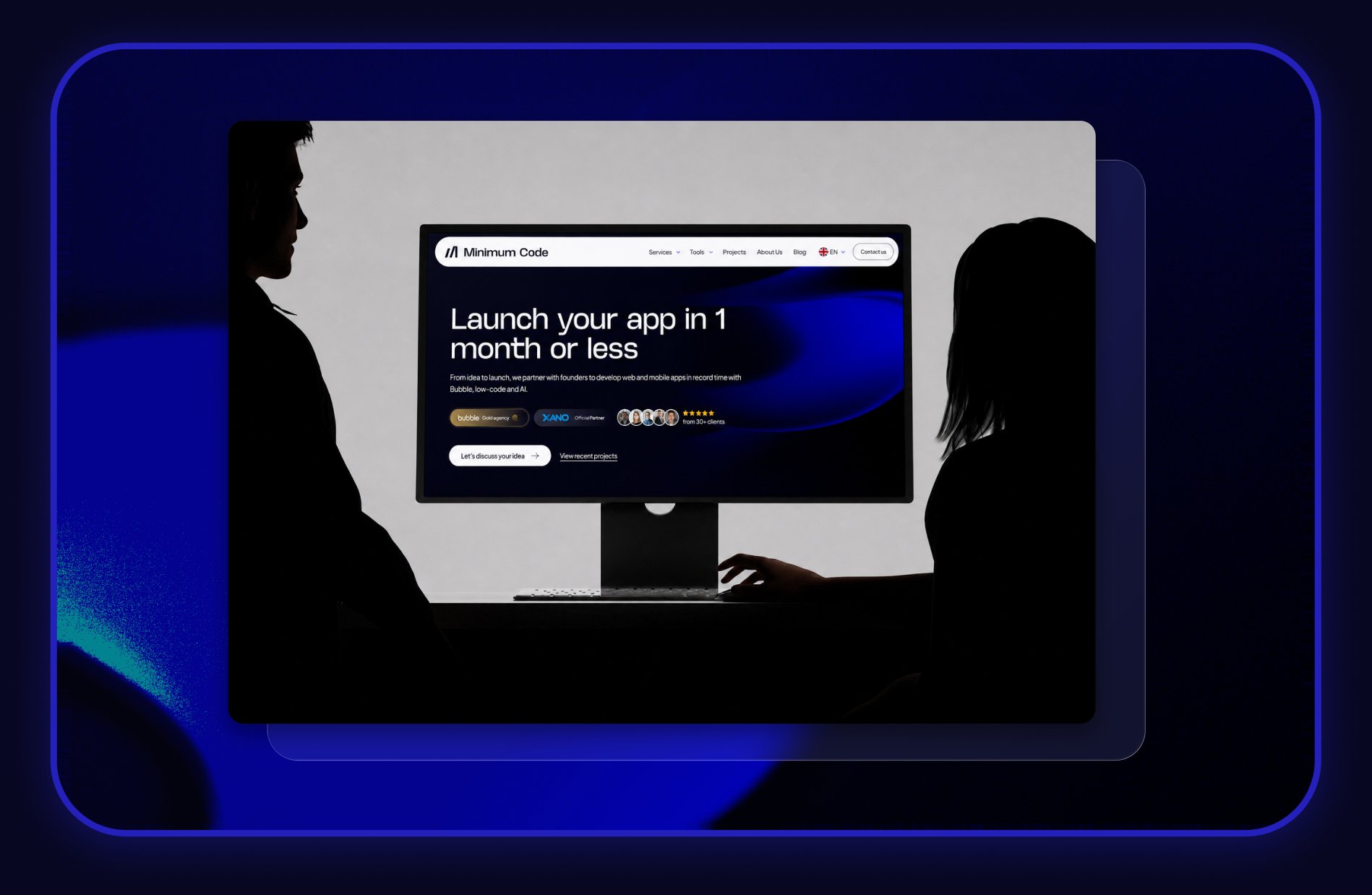 Two silhouetted colleagues at a desk viewing the Minimum Code website on a large monitor