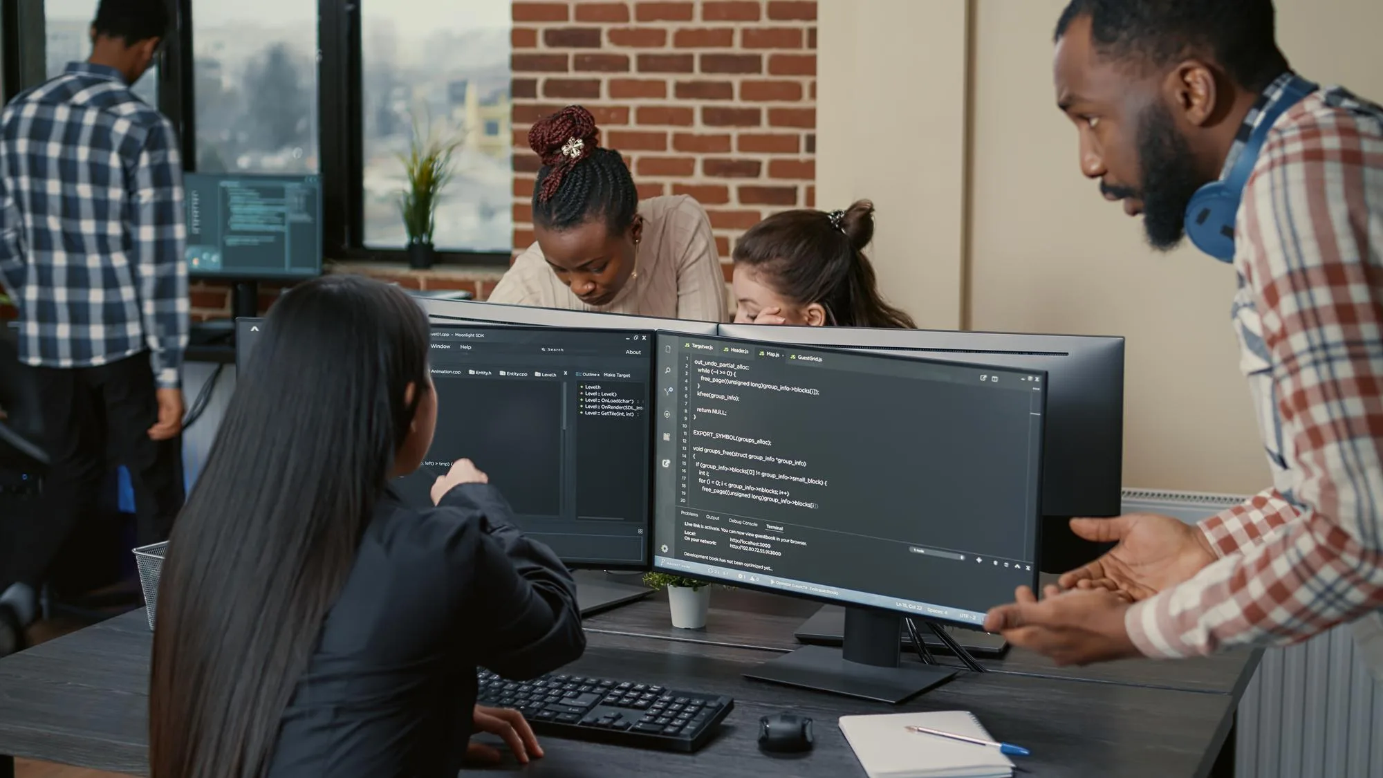 Ein Team arbeitet gemeinsam an Computern mit Code auf den Bildschirmen.
