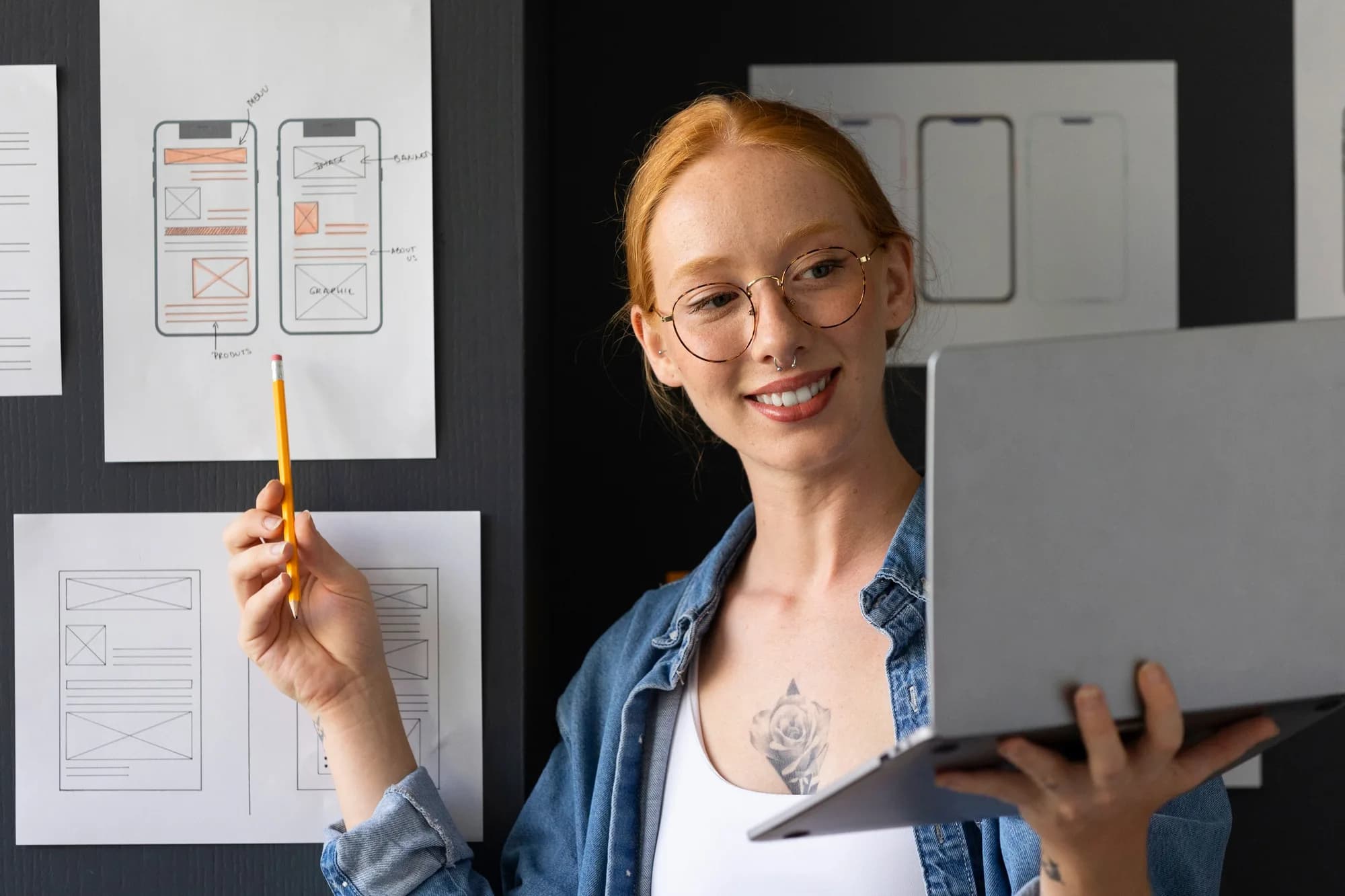 Een ontwerper bespreekt mobiele wireframes naast een laptop.
